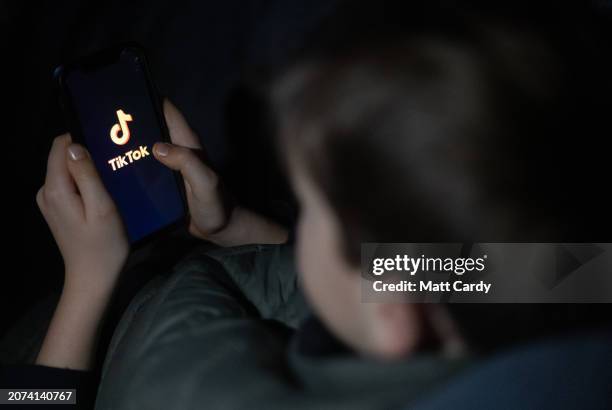 Year-old boy looks at a smartphone screen displaying the TikTok logo on March 10, 2024 in Bath, England. Following the lead of the EU Commission and...