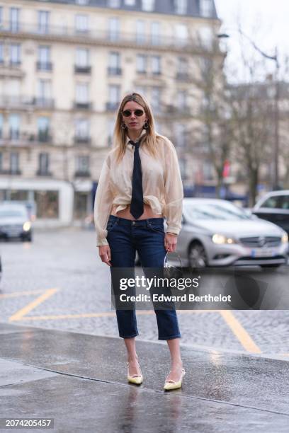 Natalia Verza wears Capri low waist dark blue denim cropped pants from Prada, a transparent gathered beige shirt from Munthe, kitten heels mule shoes...