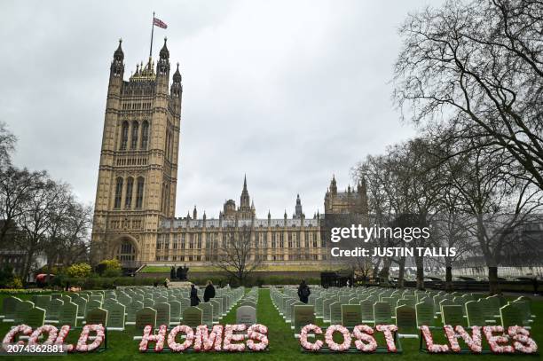 Photograph taken on March 13, 2024 shows gravestones displayed behind a sign reading "Cold Homes Cost Lives" in Victoria Tower Gardens, in front of...