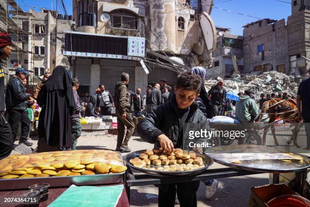 Palestinian youth sorts a tray at a street stall selling traditional sweets during the Muslim holy fasting month of Ramadan in Rafah in the southern...
