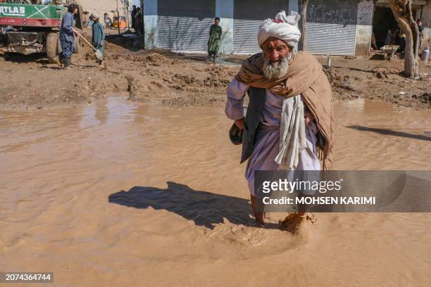 An Afghan elderly man walks through a flooded street following the flash floods after heavy rainfall in Guzara district of Herat province on March...