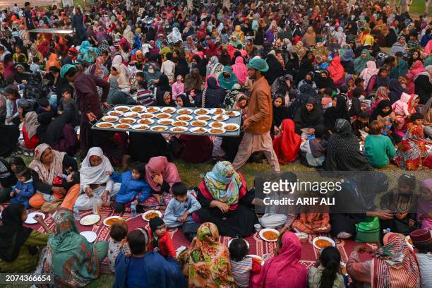 Volunteers distribute free food as Muslim devotees gather to break their fast during the Islamic holy month of Ramadan in Lahore on March 13, 2024.