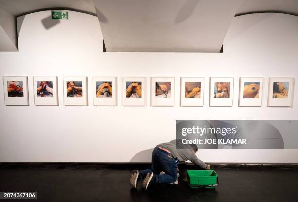 Graphic content / A worker washes the floor under the color photographs from the serie Transfusion by Guenter Brus from 1965, during a press event on...
