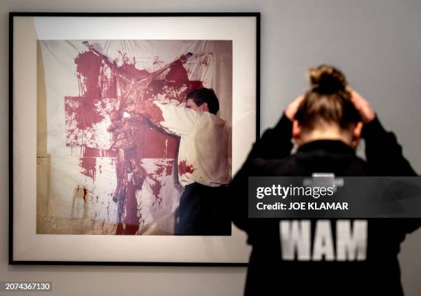 Worker stands in front of a photograph by Hermann Nitsch, a leading figure of Viennese Actionism, whose art encompassed wide-scale performances...