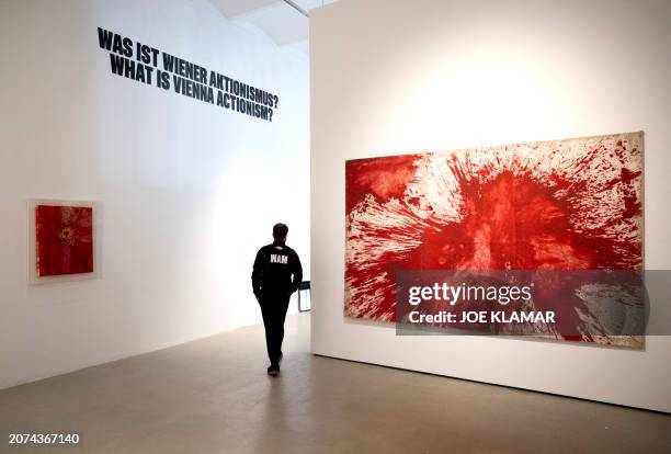 Worker walks past paintings by Hermann Nitsch, a leading figure of Viennese Actionism, whose art encompassed wide-scale performances incorporating...