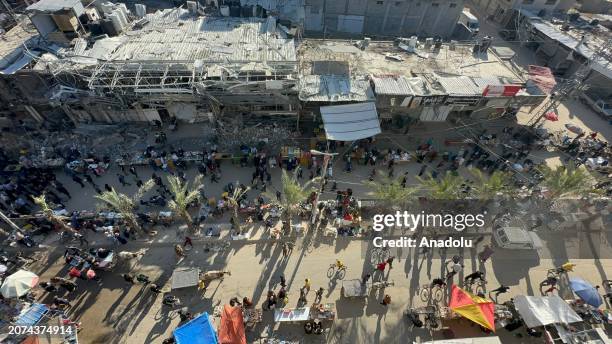 An aerial view as Palestinians at Nuseirat refugee camp doing their Ramadan shopping at the bazaar established between the destroyed buildings as...