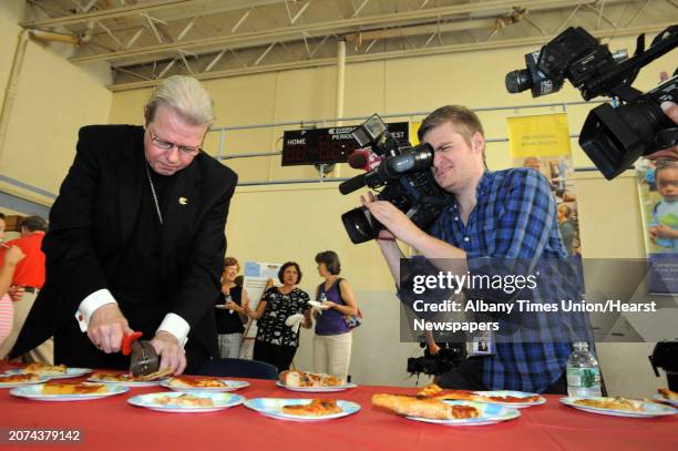 Albany Bishop Edward Scharfenberger trys various offerings from Capital Region pizza makers during the "Bishop's Choice" pizza challenge at the...