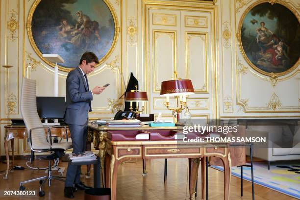 French Prime minister Gabriel Attal looks at his phone in his office at the Hotel Matignon, in Paris, on March 13, 2024. Secularism is "threatened...