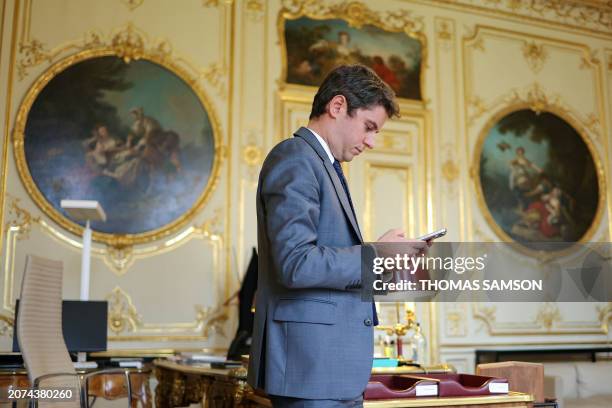 French Prime minister Gabriel Attal looks at his phone in his office at the Hotel Matignon, in Paris, on March 13, 2024. Secularism is "threatened...