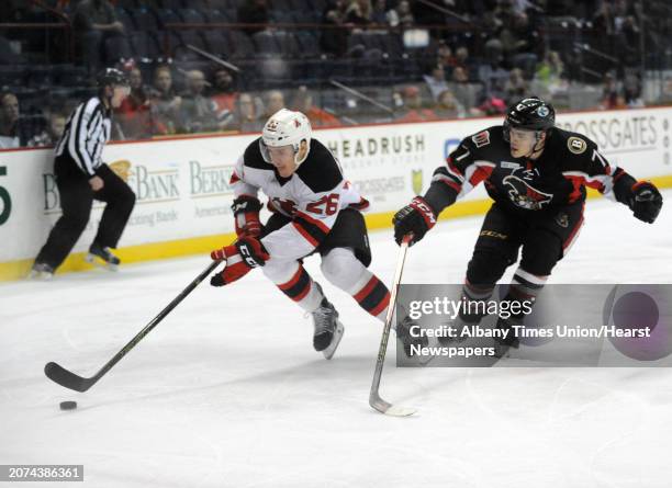 Devil Ben Thomson and Binghamton's Chris Carlisle go after the puck during their hockey game at the Times Union Center on Wednesday April 13, 2016 in...