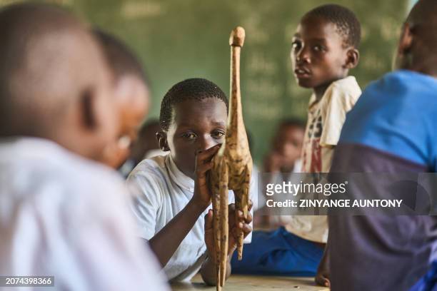 Grade three pupil, Kholwani Ndebele, plays with a broken wooden giraffe in a classroom at Mabale Primary near Hwange National Park in Hwange on March...