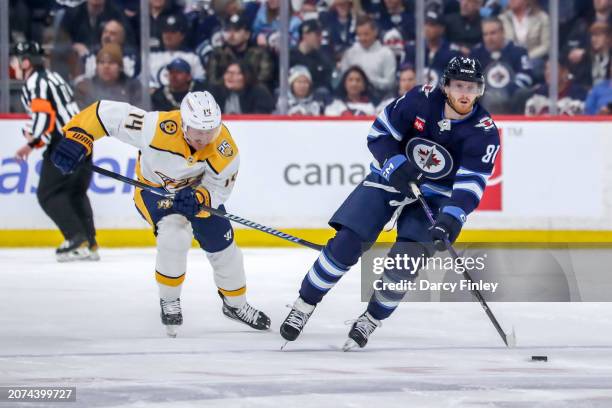 Kyle Connor of the Winnipeg Jets plays the puck down the ice as Gustav Nyquist of the Nashville Predators gives chase during second period action at...