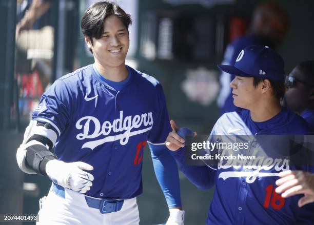 Shohei Ohtani of the Los Angeles Dodgers chats with his teammate Yoshinobu Yamamoto in the dugout during a spring training baseball game against the...