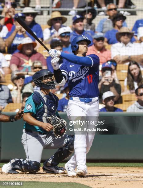 Shohei Ohtani of the Los Angeles Dodgers flies out in the first inning of a spring training baseball game against the Seattle Mariners in Glendale,...