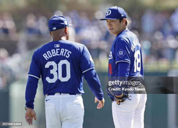 Los Angeles Dodgers pitcher Yoshinobu Yamamoto talks with manager Dave Roberts during the fifth inning of a spring training baseball game against the...