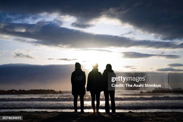 People watches the sunrise at a beach of Arahama district on the 13th anniversary of the Great East Japan Earthquake on March 11, 2024 in Sendai,...