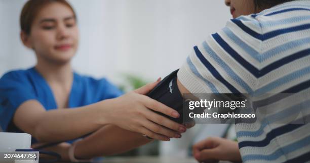 doctor measuring blood pressure, young woman undergoes annual medical check-up - blood pressure photos et images de collection