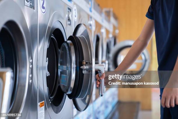 the boy loading washing machine. - man washing basket child stock pictures, royalty-free photos & images