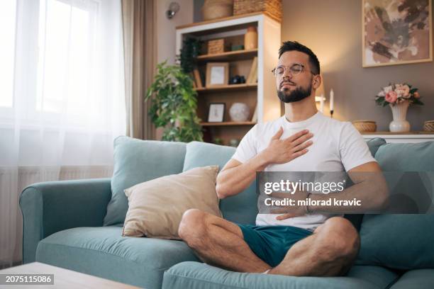 a man sits at home and practices yoga. - home workout stock pictures, royalty-free photos & images