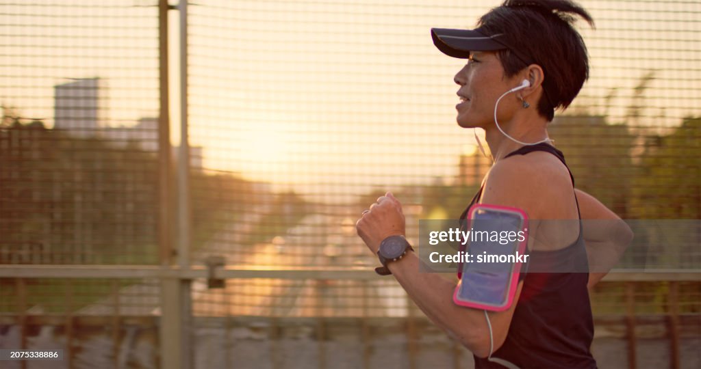 Athletic Asian woman running in the city at sunset