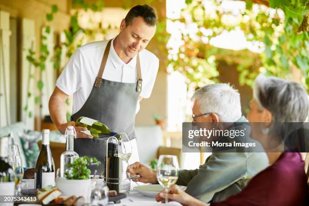 sommelier pouring wine for woman and man at porch - servente de vinho imagens e fotografias de stock