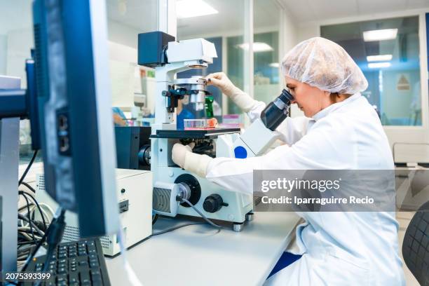 doctor analyzing samples using microscope in a pharmaceutical industry laboratory - industria-farmaceutica fotografías e imágenes de stock