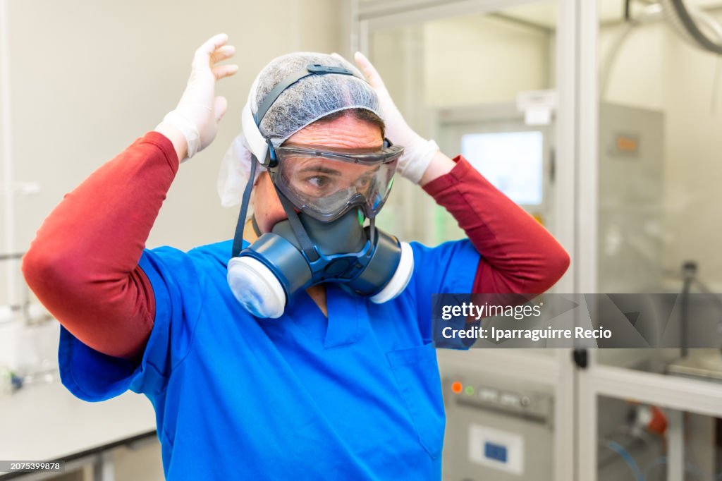 Scientist putting on protective gear to enter a machine for electrical tests with plasma