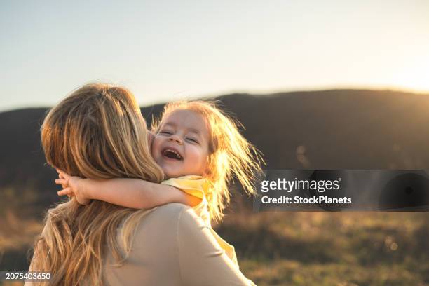 glückliches mädchenkind, das mama in der natur umarmt - baby lachen natur stock-fotos und bilder