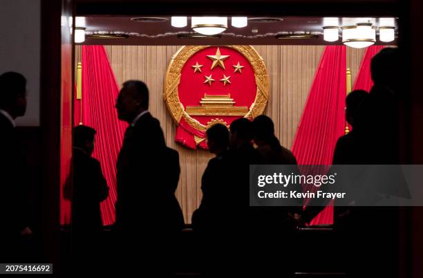 The National Emblem is seen as delegates and security stand in the entranceway to the auditorium before the closing session of the NPC, or National...