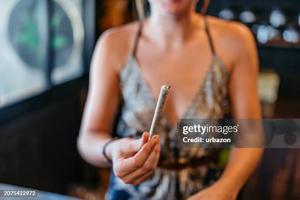 young woman giving a marijuana joint to a customer in a cannabis shop in thailand - stampot stockfoto's en -beelden