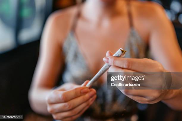 giovane donna che fa uno spinello di marijuana in un negozio di cannabis in thailandia - spinello foto e immagini stock