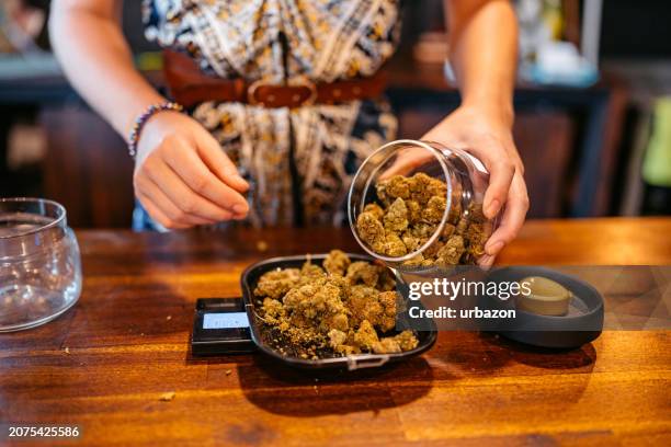 young woman weighing herbal cannabis on a scale in a cannabis shop in thailand - stampot stockfoto's en -beelden