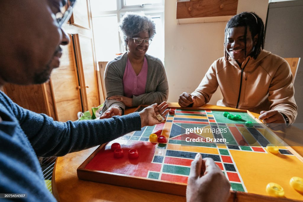 African family with teenage kids playing board game together