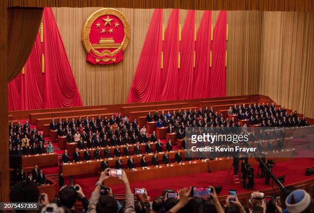 Chinese President Xi Jinping, centre, senior leaders and delegates stand during the national anthem at the closing session of the NPC, or National...