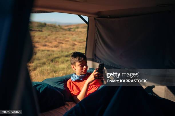 young boy chatting with smartphone in the van in the red canyon of teruel, spain. - geology technology stock pictures, royalty-free photos & images