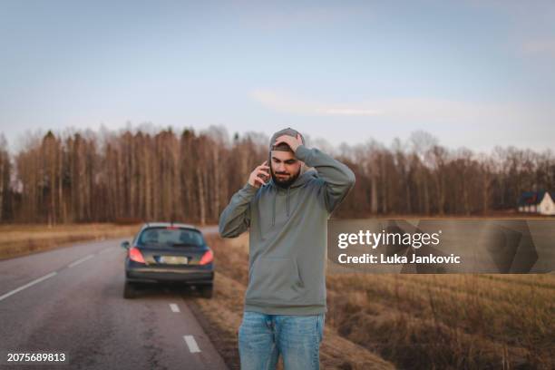 hombre estresado pidiendo ayuda mientras está varado al costado de la carretera - borde de la carretera fotografías e imágenes de stock