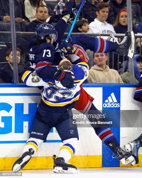 Jake Neighbours of the St. Louis Blues checks Matt Rempe of the New York Rangers during the third period at Madison Square Garden on March 09, 2024...