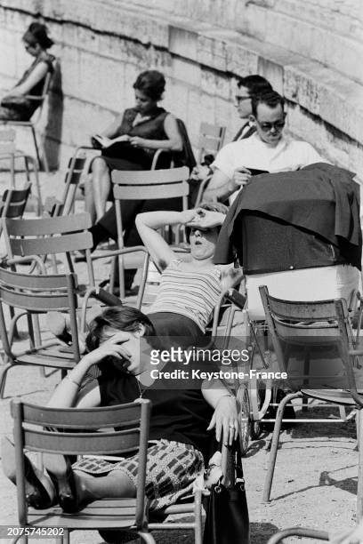 Parisiens profitant du soleil sur les chaises du jardin des Tuileries à Paris, le 11 mai 1964.
