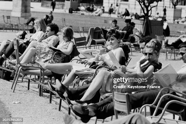 Parisiens profitant du soleil sur les chaises du jardin des Tuileries à Paris, le 11 mai 1964.