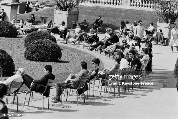 Parisiens profitant du soleil sur les chaises du jardin des Tuileries à Paris, le 11 mai 1964.