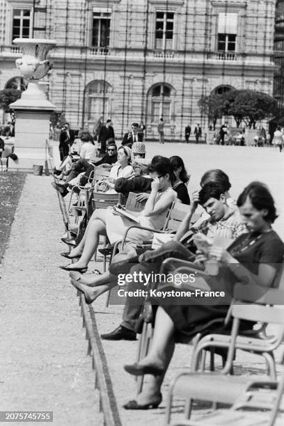 Parisiens profitant du soleil sur les chaises du jardin des Tuileries à Paris, le 11 mai 1964.