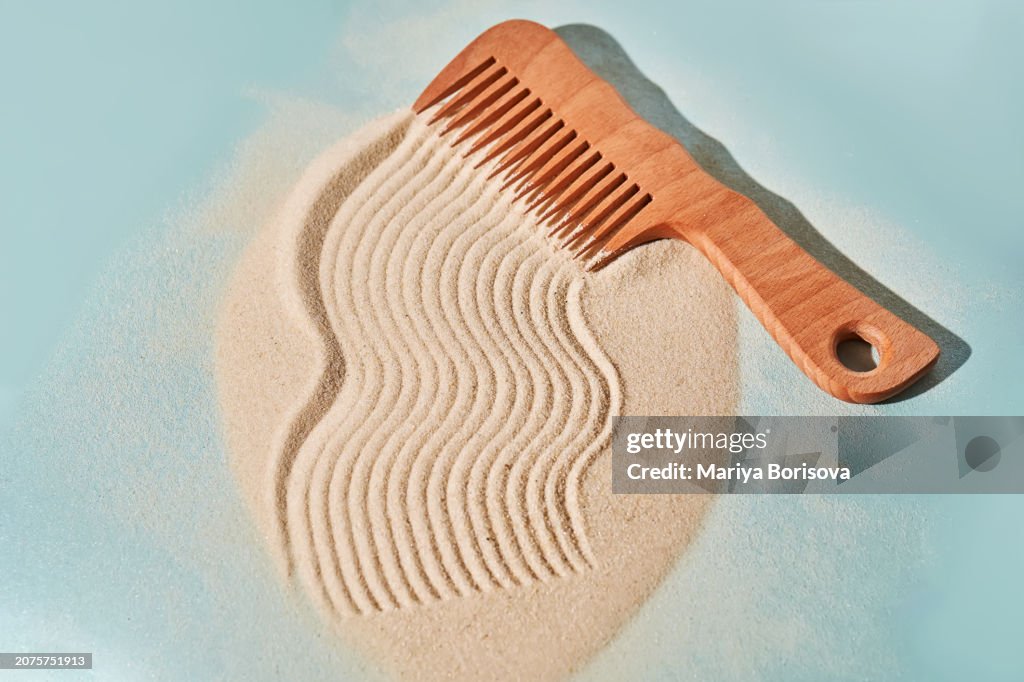 Wooden comb on the sand with marks.