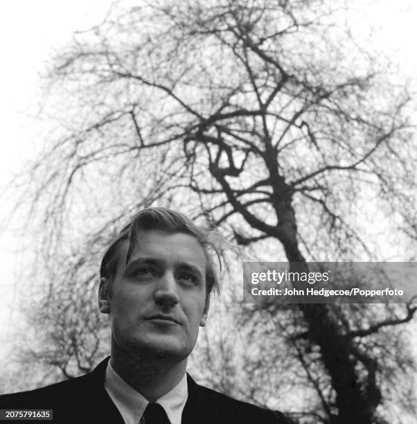 English poet and writer Ted Hughes stands on a residential street in London in 1959.