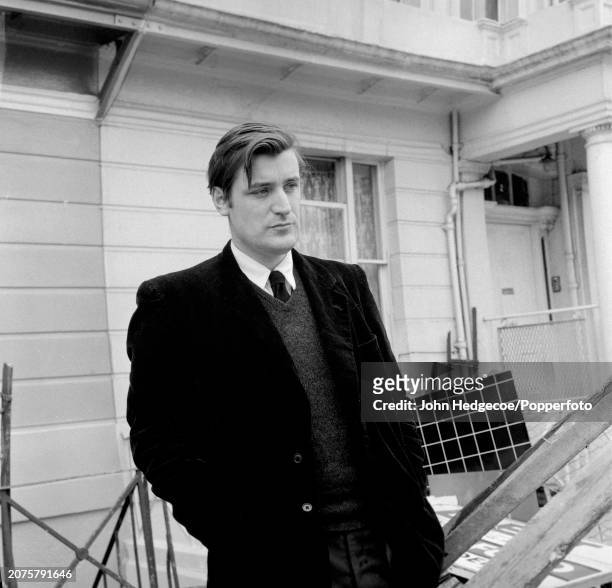 English poet and writer Ted Hughes stands on a residential street in London in 1959.