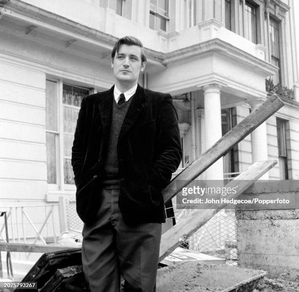English poet and writer Ted Hughes stands on a residential street in London in 1959.