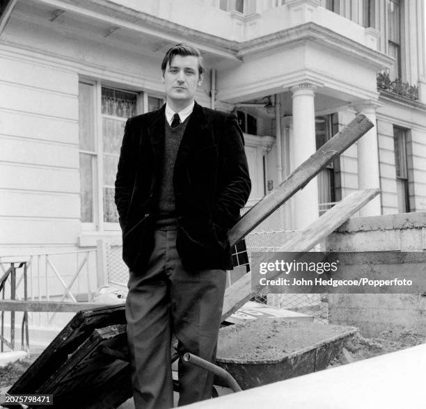 English poet and writer Ted Hughes stands on a residential street in London in 1959.