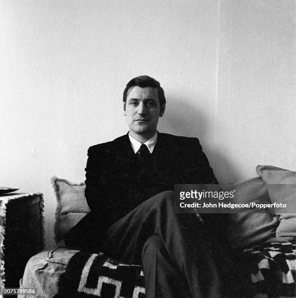 English poet and writer Ted Hughes seated on a sofa inside a house in London in 1959.