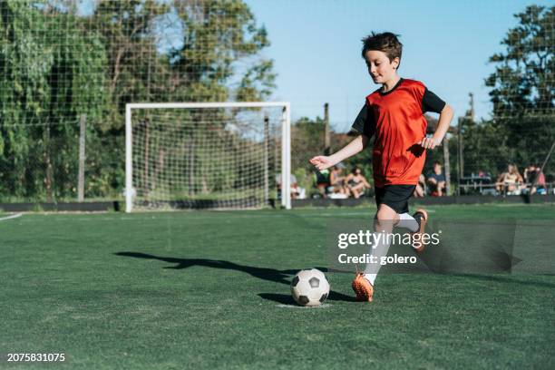 soccer boy kicking the ball on field - red white jersey stock pictures, royalty-free photos & images