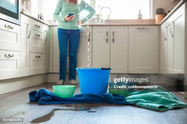 worried home owner dealing with water leak in the kitchen - vatten bildbanksfoton och bilder