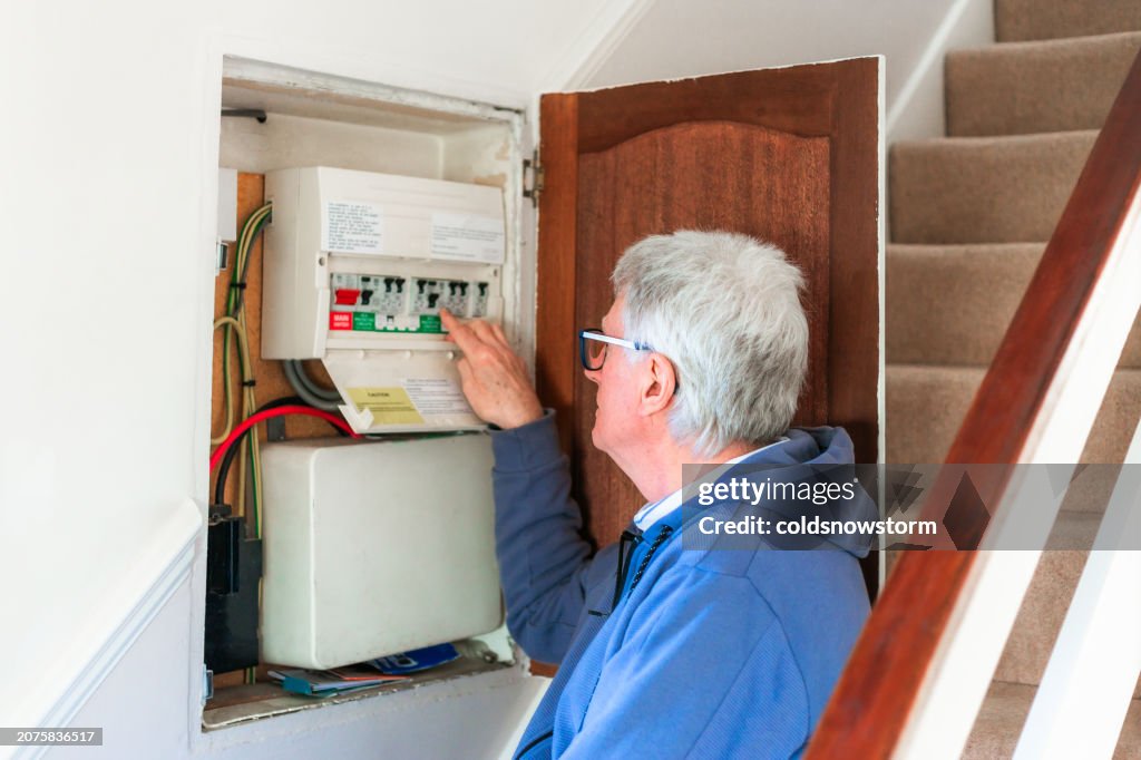 Senior man checking electric fuses at home